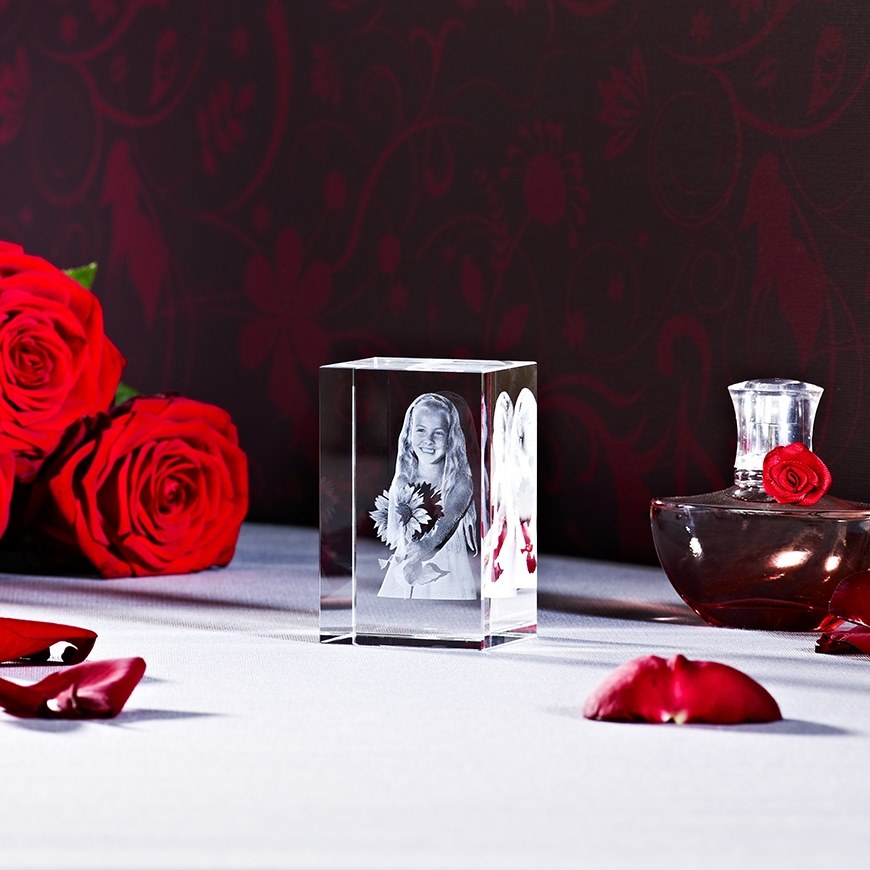 Kristallwürfel mit Gravur eines Mädchens mit Blumen, umgeben von roten Rosen und Glasflakon mit roter Rose