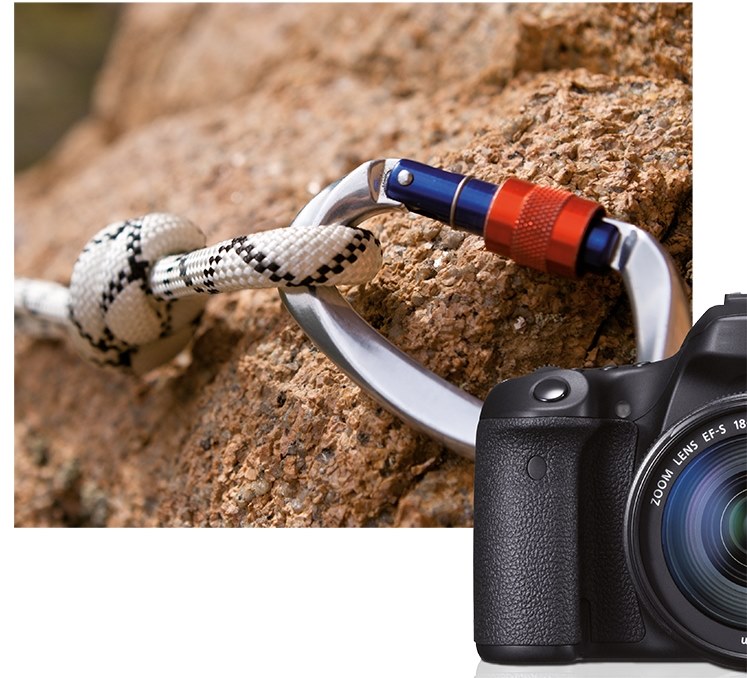 Karabinerhaken befestigt an Kletterseil und Felswand, hält eine Kamera mit Zoomobjektiv